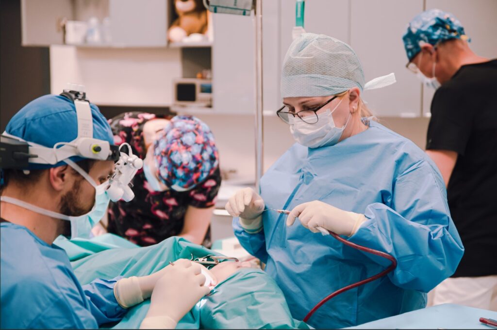 Obrazek ma cel informacyjny: laryngolog podczas operacji trzeciego migdałka gardłowego. Adenotomia.